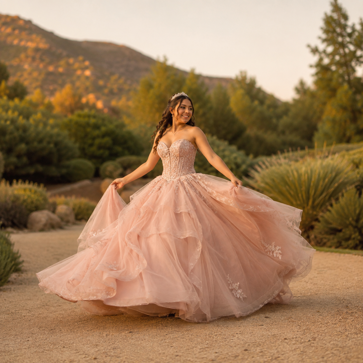 Quinceañera holding a flowing pink dress in a green landscape